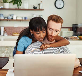 woman and a man at a table looking at a laptop