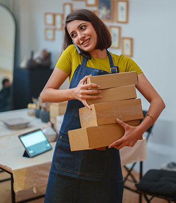 Woman wearing apron on mobile holding boxes