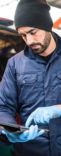 Man in coveralls looking at tablet