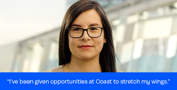 Woman wearing glasses with long brown hair in a beige suit and black shirt smiling. Text on a blue background reads, "I've been given opportunities at Coast to stretch my wings.