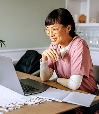 Woman in scrubs looking at laptop