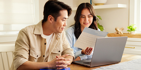 Man and woman sitting at table looking at a laptop and a Coast Capital document