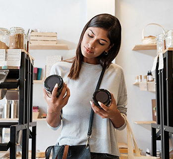 dark haired woman in a store looking at 2 jars