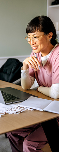 Woman in scrubs looking at laptop