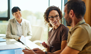 Financial professional reviewing documents with two clients during an in-person consultation at a meeting table.