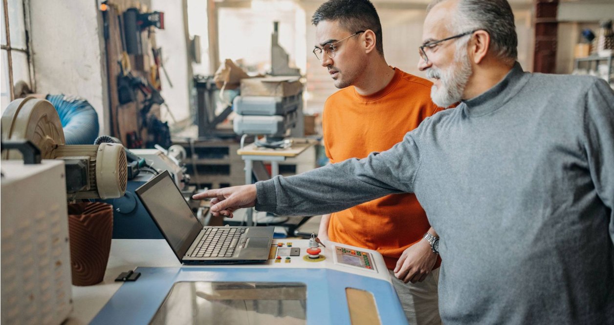two men standing at laptop