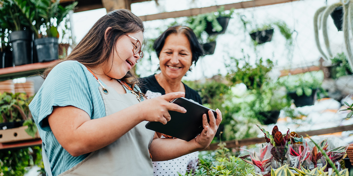Two women in garden centre looking at a tablet device