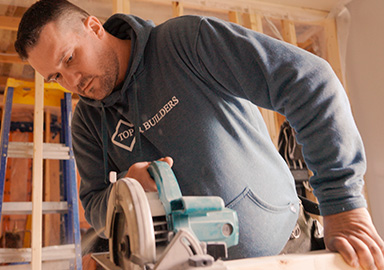 man using a circular saw on a construction site