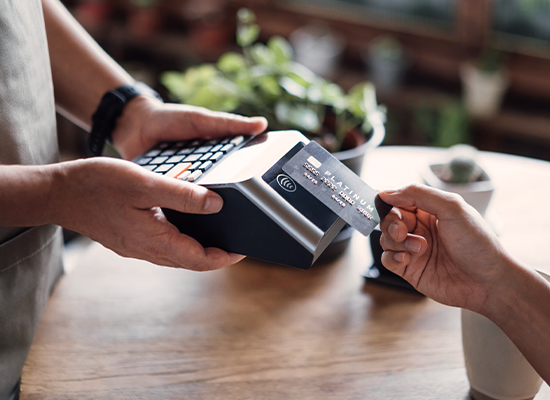 Customer making a card payment using a point-of-sale terminal at a retail checkout counter.